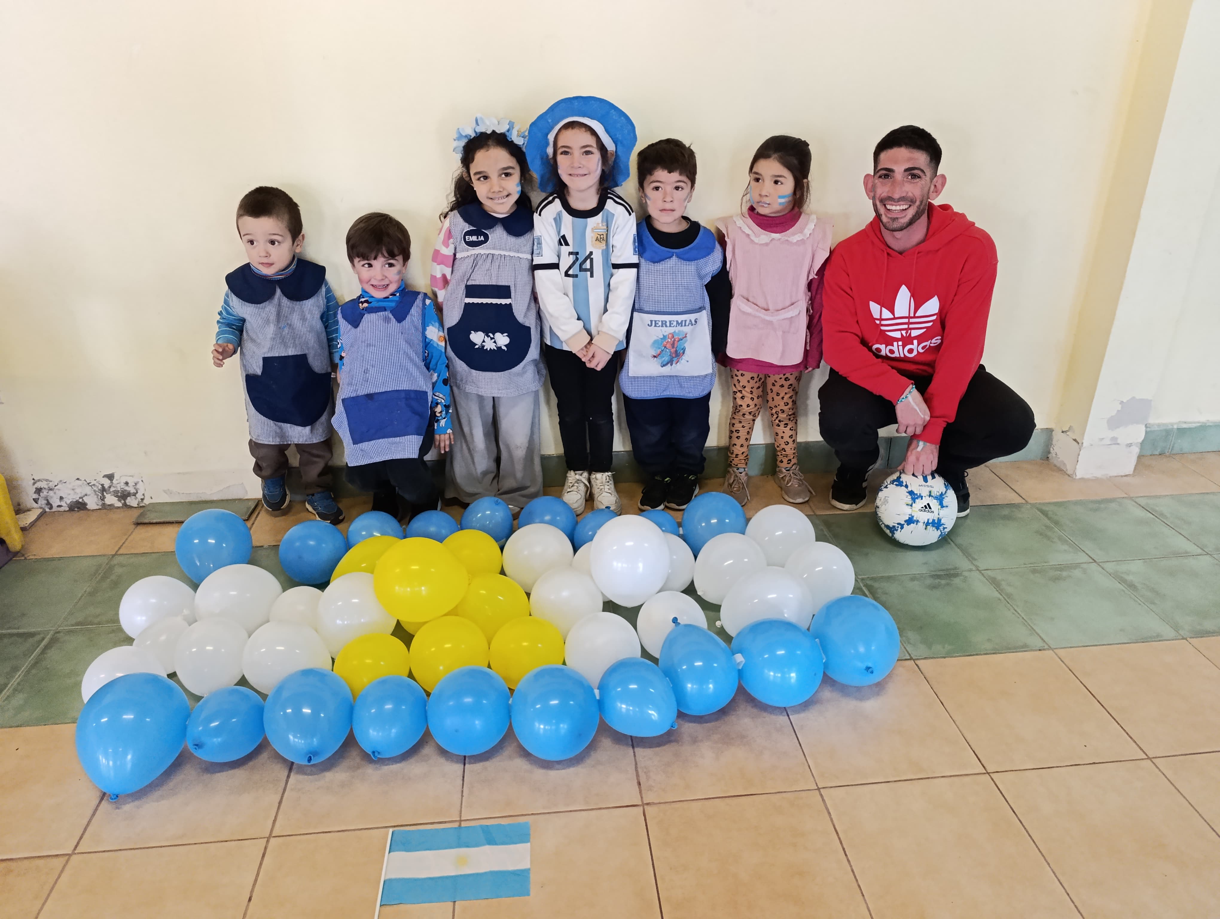 Grupo de niños junto a una decoración con globos