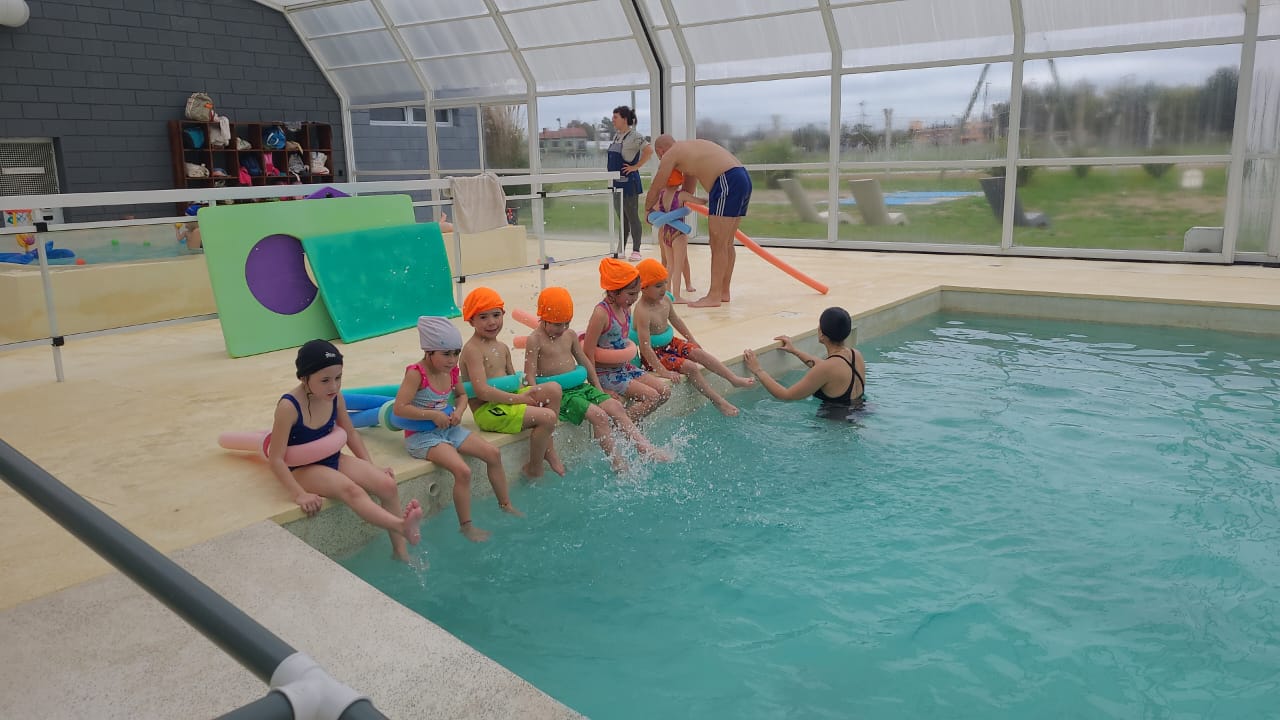 Niños durante una actividad de natación acompañados por adultos
